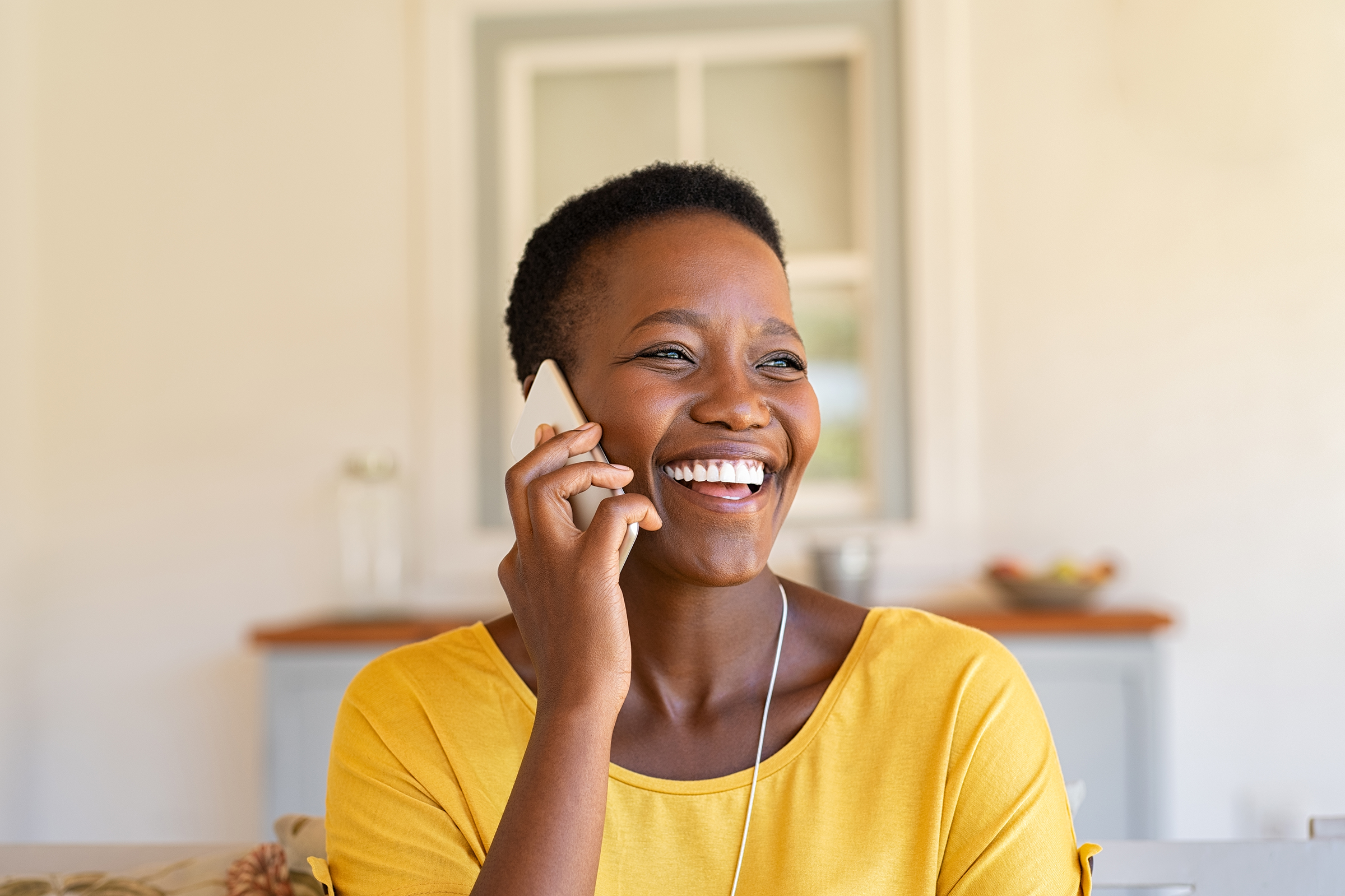 Woman with a mobile phone held to ear and smiling.