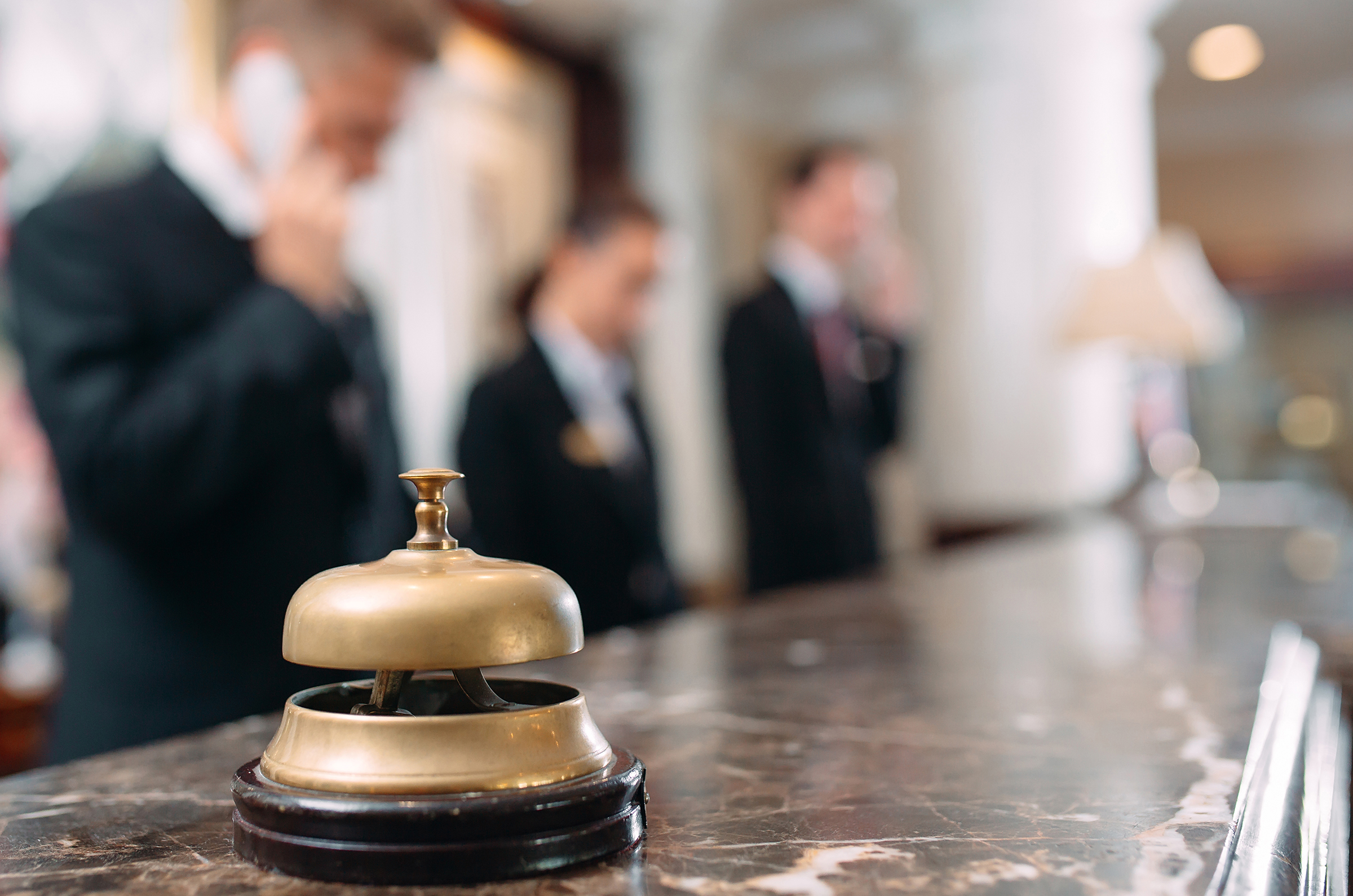 Hotel staff using phones at the reception desk.